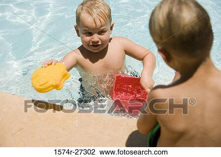 Boy playing with his friend at swimming pool View Large Photo Image Stock Image - Boy playing with his friend at swimming pool. Fotosearch