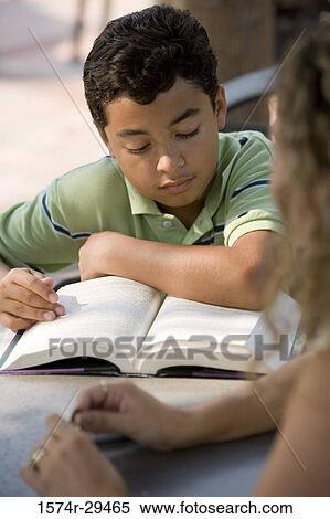 Stock Photography - Boy reading book while young woman in foreground. Fotosearch