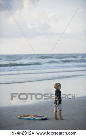 Picture - Boy walking with surfboard at the beach. Fotosearch