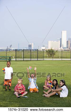 Boys and girls sitting on grass and eating lollipop View Large Photo Image Stock Image - Boys and girls sitting on grass and eating lollipop. Fotosearch