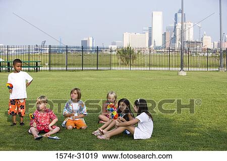 Boys and girls sitting on grass and eating lollipop View Large Photo Image Stock Photo - Boys and girls sitting on grass and eating lollipop. Fotosearch