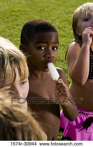 Boys and girls standing together and eating flavored ice View Large Photo Image Picture - Boys and girls standing together and eating flavored ice. Fotosearch