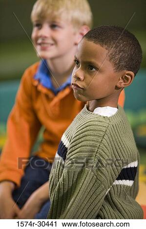 Stock Image - Boys sitting in casuals looking away. Fotosearch