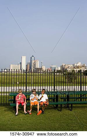 Boys sitting on bench and eating lollipops View Large Photo Image Stock Photo - Boys sitting on bench and eating lollipops. Fotosearch