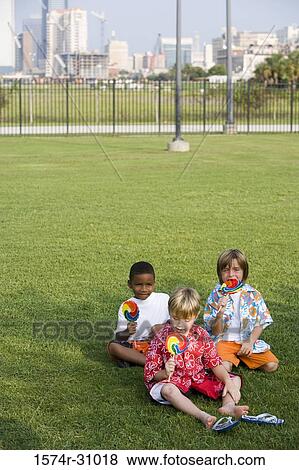 Boys sitting on grass and eating lollipop View Large Photo Image Stock Photo - Boys sitting on grass and eating lollipop. Fotosearch