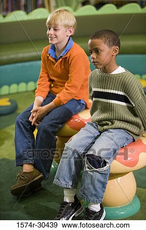 Stock Photo - Boys sitting on stools and looking away. Fotosearch