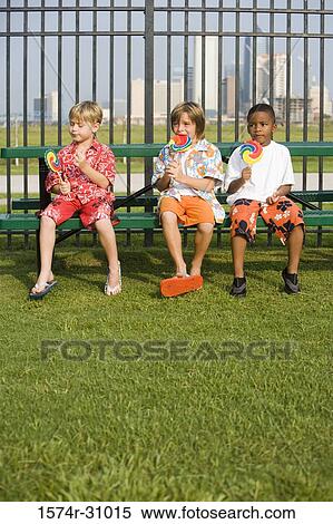 Boys sitting on the bench and eating lollipop View Large Photo Image Stock Photography - Boys sitting on the bench and eating lollipop. Fotosearch