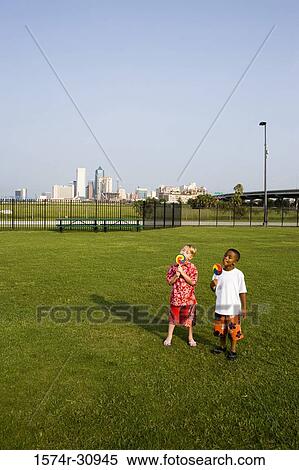 Boys standing on grass and eating lollipops View Large Photo Image Stock Photography - Boys standing on grass and eating lollipops. Fotosearch