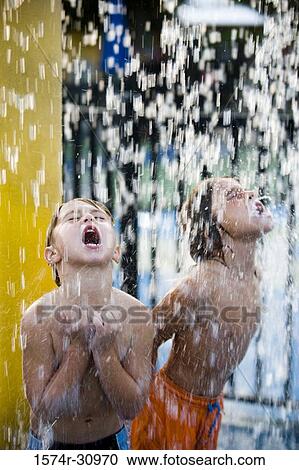 Boys standing together under a shower with mouth open View Large Photo Image Stock Image - Boys standing together under a shower with mouth open. Fotosearch