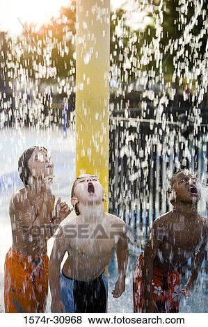 Boys standing together under a shower with mouth open View Large Photo Image Stock Photo - Boys standing together under a shower with mouth open. Fotosearch