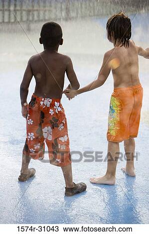 Stock Image - Boys standing under a shower. Fotosearch