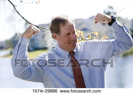 Business man flexing his muscles with the river in the background View Large Photo Image Stock Photograph - Business man flexing his muscles with the river in the background. Fotosearch