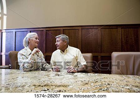 Business people discussing by conference table in an office View Large Photo Image Stock Photo - Business people discussing by conference table in an office. Fotosearch