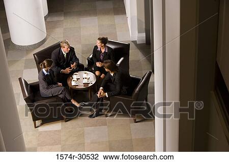 Business people discussing by table in an office View Large Photo Image Stock Image - Business people discussing by table in an office. Fotosearch