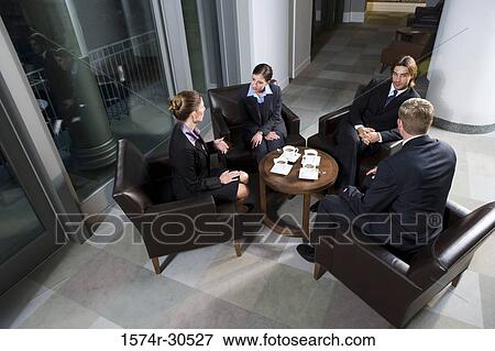 Business people discussing by table in an office View Large Photo Image Stock Photo - Business people discussing by table in an office. Fotosearch