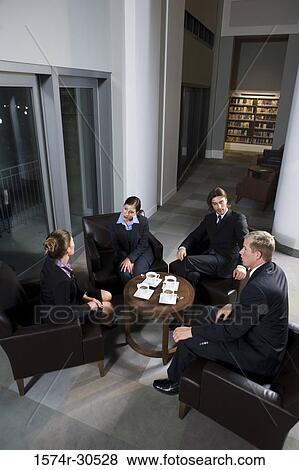 Stock Photo - Business people discussing by table in an office. Fotosearch