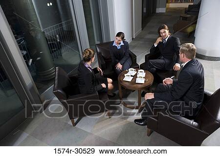 Business people discussing by table in an office View Large Photo Image Stock Photo - Business people discussing by table in an office. Fotosearch