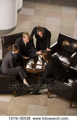 Stock Photo - Business people discussing by table in an office. Fotosearch