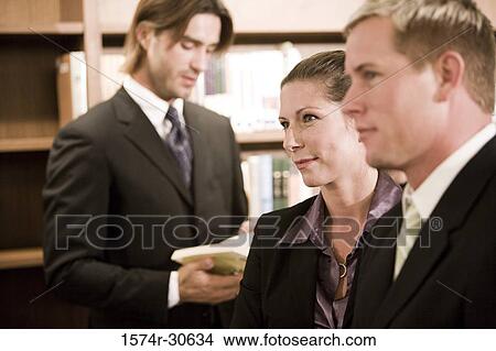 Business people looking away while businessman reading a book View Large Photo Image Picture - Business people looking away while businessman reading a book. Fotosearch