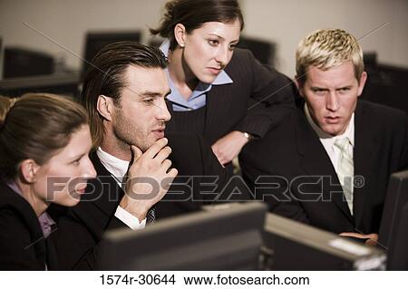 Picture - Business people watching desktop pc in an office. Fotosearch