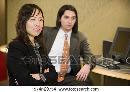 Businessman and a woman smiling in an office View Large Photo Image Picture - Businessman and a woman smiling in an office. Fotosearch