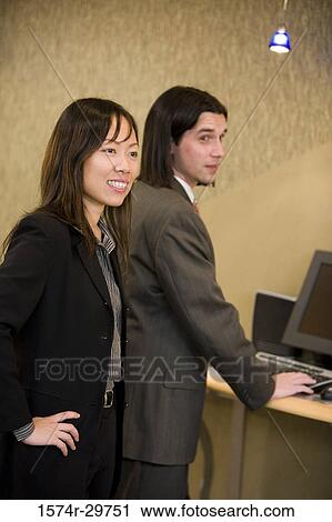 Businessman and a woman smiling in an office View Large Photo Image Stock Image - Businessman and a woman smiling in an office. Fotosearch