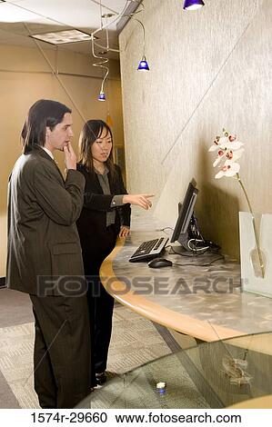 Businessman and businesswoman looking at a computer monitor in an office View Large Photo Image Stock Image - Businessman and businesswoman looking at a computer monitor in an office. Fotosearch
