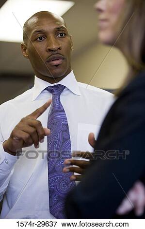 Stock Photo - Businessman explaining to a businesswoman in an office. Fotosearch