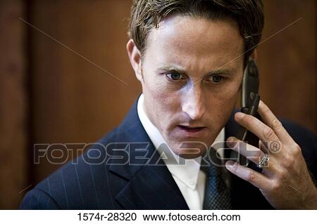 Businessman holding a mobile phone in an office View Large Photo Image Stock Image - Businessman holding a mobile phone in an office. Fotosearch
