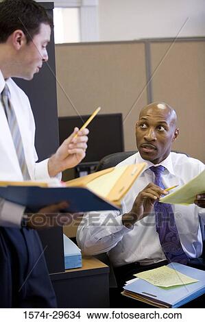 Businessman in conversation with colleague in an office View Large Photo Image Picture - Businessman in conversation with colleague in an office. Fotosearch