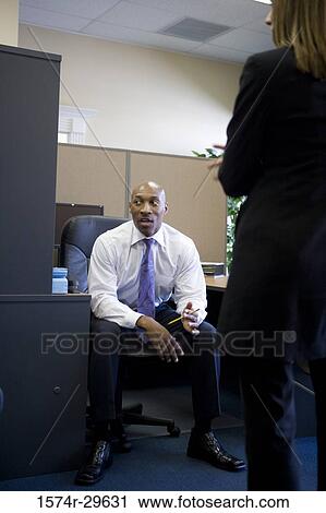 Businessman in conversation with colleague in an office View Large Photo Image Stock Image - Businessman in conversation with colleague in an office. Fotosearch