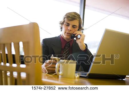 Businessman in full suit using mobile phone and laptop in an office View Large Photo Image Stock Image - Businessman in full suit using mobile phone and laptop in an office. Fotosearch
