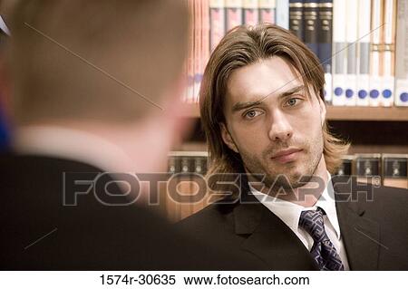 Businessman looking his colleague in an office View Large Photo Image Stock Photography - Businessman looking his colleague in an office. Fotosearch