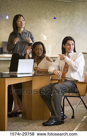 Stock Photo - Businessman pointing towards businesswomen in an office. Fotosearch