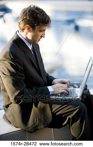 Businessman sitting and using laptop computer View Large Photo Image Stock Image - Businessman sitting and using laptop computer. Fotosearch