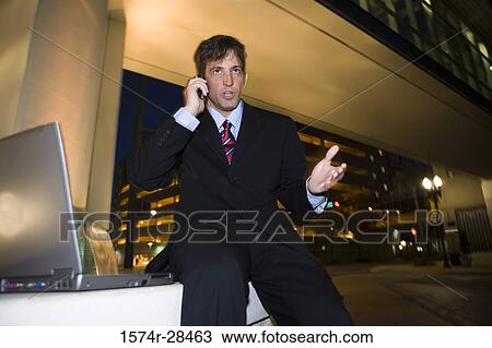 Businessman sitting by laptop and communicating on mobile phone View Large Photo Image Stock Image - Businessman sitting by laptop and communicating on mobile phone. Fotosearch