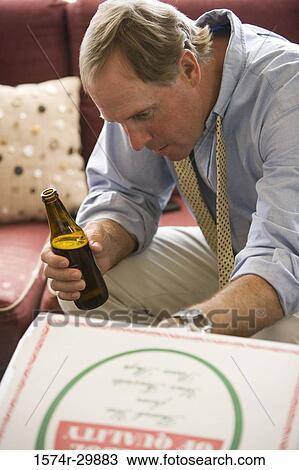 Businessman sitting on a sofa holding a beer bottle View Large Photo Image Stock Image - Businessman sitting on a sofa holding a beer bottle. Fotosearch