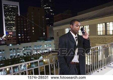 Businessman standing in a balcony and using a mobile phone View Large Photo Image Stock Image - Businessman standing in a balcony and using a mobile phone. Fotosearch