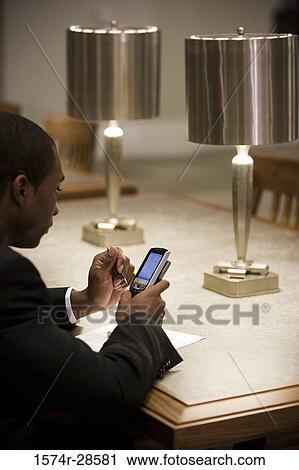 Businessman using a mobile phone in an office View Large Photo Image Stock Image - Businessman using a mobile phone in an office. Fotosearch