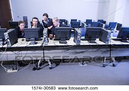 Stock Image - Businessman with colleagues using computer in an office. Fotosearch