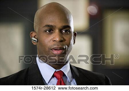Businessman with handsfree device in an office View Large Photo Image Stock Image - Businessman with handsfree device in an office. Fotosearch