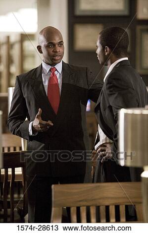 Stock Image - Businessmen conversing in an office. Fotosearch