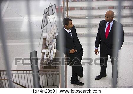Stock Image - Businessmen conversing on staircase. Fotosearch