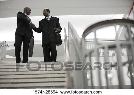 Businessmen handshaking on staircase in an office View Large Photo Image Picture - Businessmen handshaking on staircase in an office. Fotosearch