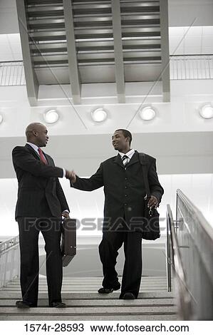 Businessmen handshaking on staircase in an office View Large Photo Image Stock Image - Businessmen handshaking on staircase in an office. Fotosearch