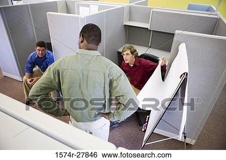 Stock Photograph - Businessmen in conversation using chart board in an office. Fotosearch