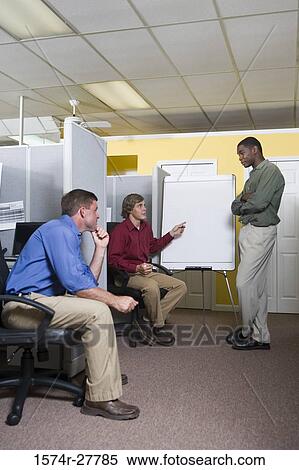 Stock Photography - Businessmen in conversation using chart board in an office. Fotosearch
