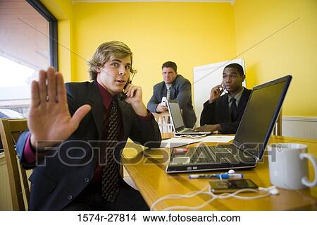Businessmen in full suit using mobile phone and laptop in an office View Large Photo Image Picture - Businessmen in full suit using mobile phone and laptop in an office. Fotosearch