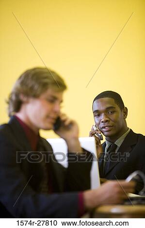Businessmen in full suit using mobile phone and laptop in an office View Large Photo Image Stock Image - Businessmen in full suit using mobile phone and laptop in an office. Fotosearch