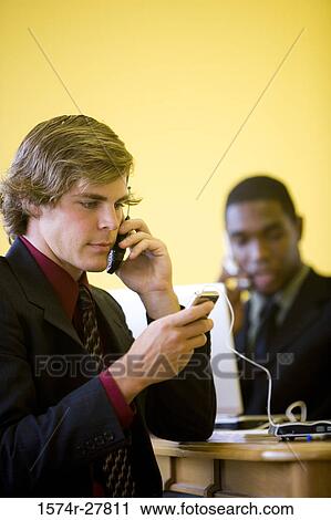 Businessmen in full suit using mobile phone and laptop in an office View Large Photo Image Stock Image - Businessmen in full suit using mobile phone and laptop in an office. Fotosearch